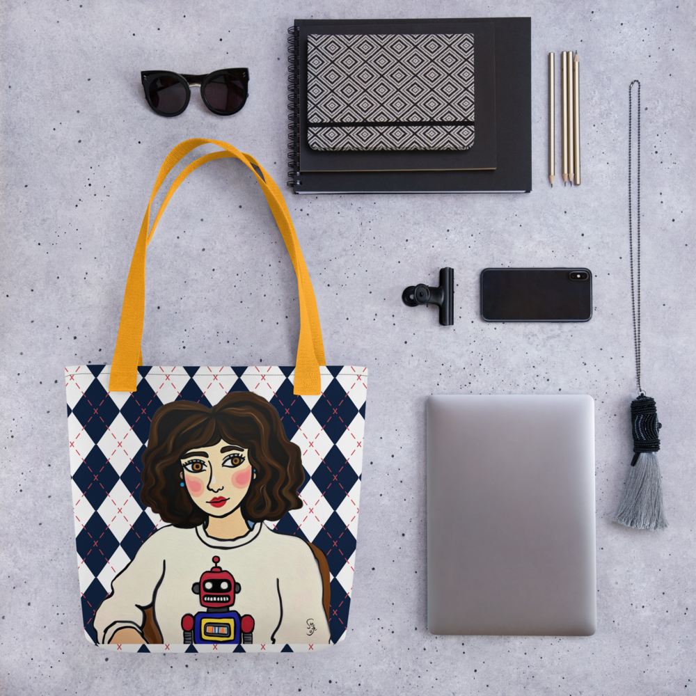 Tote bag with a graphic design of a person wearing a robot sweater, placed on a gray surface with other items.