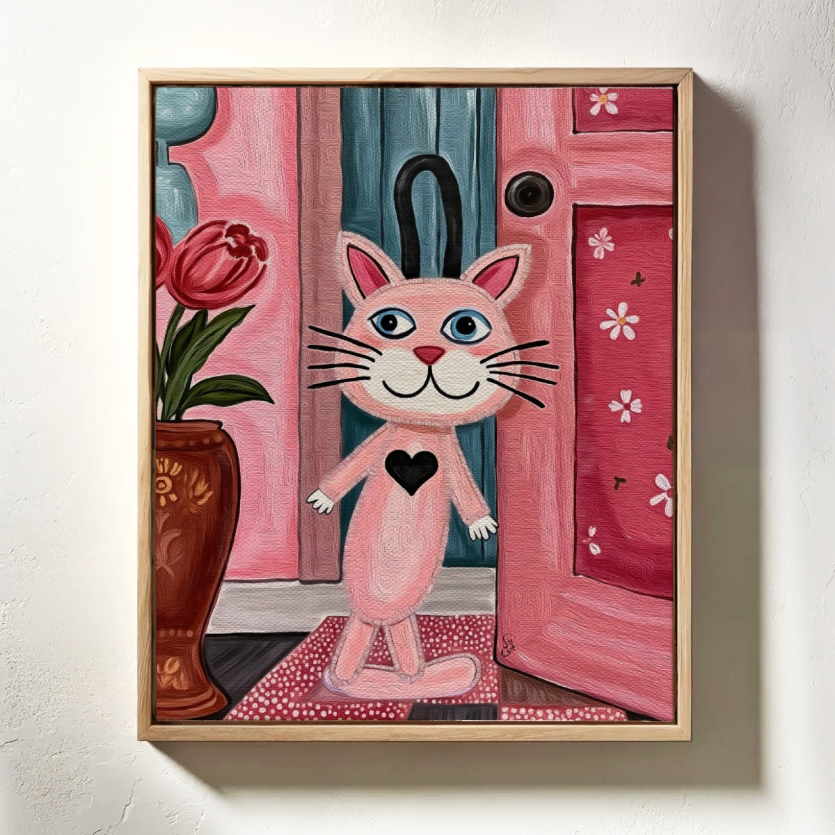 Framed artwork of a pink cat with a black heart on a white wall